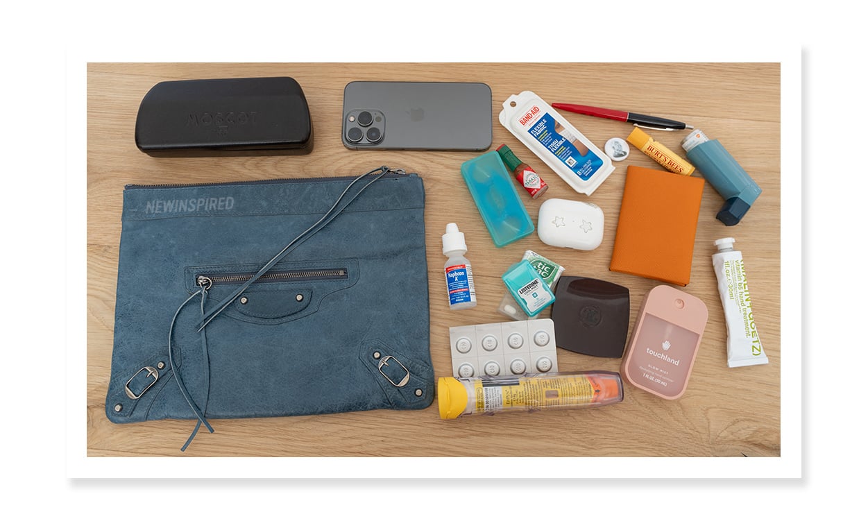 Demonstrating what can fit in a 2003 Blue Jean Balenciaga Flat Clutch; eyeglasses case, iPhone, bandaids, wallet, etc.